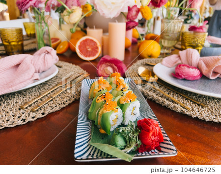 Green dragon rolls lie on a bamboo leaf on a rectangular dish on the table 104646725