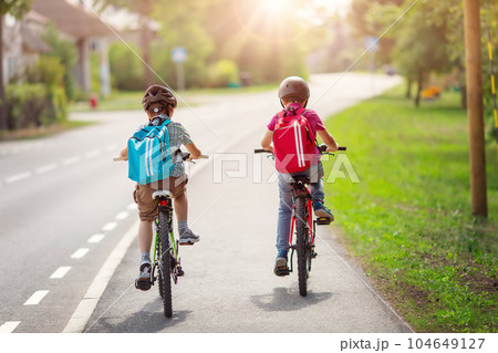 Two boys with backpacks on bicycles going to school. Two boys with backpacks on bicycles going to school. 104649127