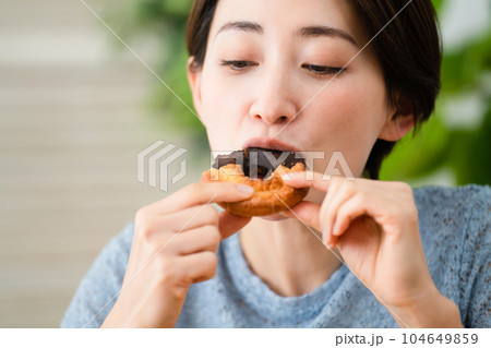 ドーナツを食べる若い女性　飲食イメージ	 104649859