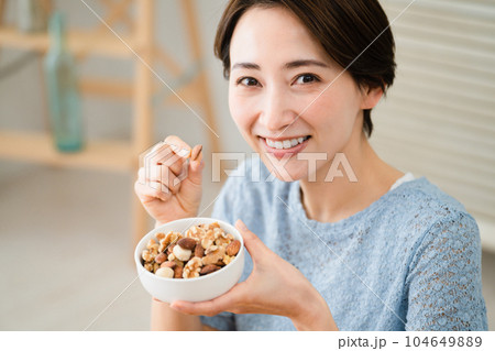 ミックスナッツを食べる若い女性　飲食イメージ 104649889