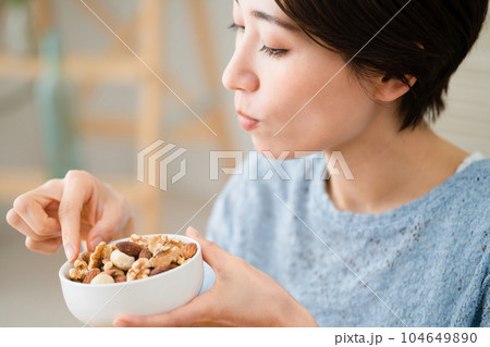 ミックスナッツを食べる若い女性　飲食イメージ 104649890