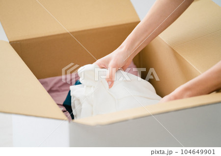 段ボールから荷物を取り出す若い女性　引っ越しイメージ	 104649901