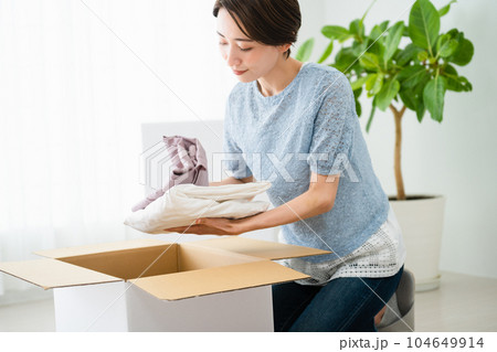 段ボールから荷物を取り出す若い女性　引っ越しイメージ	 104649914