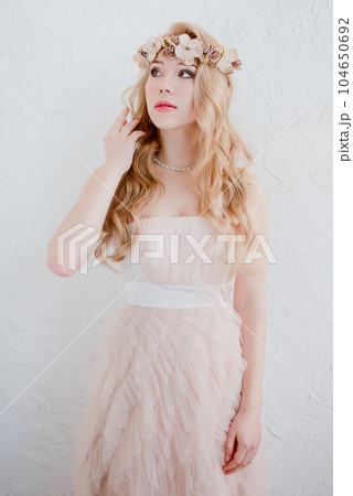 picture of young blonde woman wearing wreath of flowers, spring tender and romantic portrait, fashion retouched shot 104650692