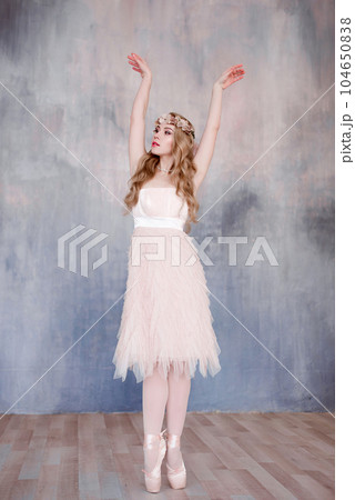 Beautiful legs of young ballerina dancing at white wooden floor background, with copy space. Ballet practice. Beautiful slim graceful ballet dancer. Spring and romantic atmosphere Beautiful legs of young ballerina dancing at white wooden floor background, with copy space. Ballet practice. Beautiful slim graceful ballet dancer. Spring and romantic atmosphere 104650838