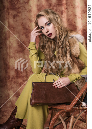 glamorous portrait of a beautiful young woman in a fur vest holding a bag 104650923