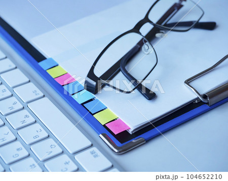 テーブルに置かれたバインダー、書類、パソコン、メガネ 104652210