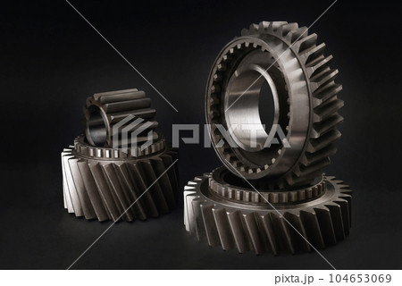 Gears. Cogwheels for a car gearbox. On a black background, selective focus Gears. Cogwheels for a car gearbox. On a black background, selective focus 104653069