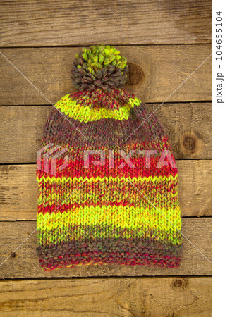 Handmade wool knitted winter colored hat, on wooden background 104655104