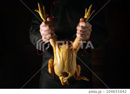 Raw rooster in the chef hand. Cock presentation before preparing a delicious dish in the restaurant kitchen. Chicken selection before frying. 104655842