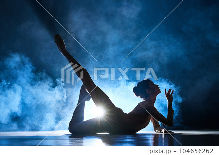Tenderness and sensuality. Graceful, beautiful, elegant woman, ballerina making performance against dark blue background with spotlight Tenderness and sensuality. Graceful, beautiful, elegant woman, ballerina making performance against dark blue background with spotlight 104656262