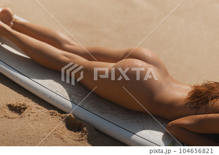 Close-up of Tanned Naked Surf Girl on Surfboard During Beach Relax 104656821