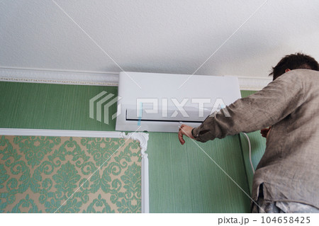 without a face. A man installs an indoor unit air conditioner.  104658425