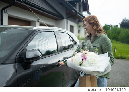 Female happy lady with bouquet of flowers near car outdoors. Sexy carefree woman posing on the street background Female happy lady with bouquet of flowers near car outdoors. Sexy carefree woman posing on the street background 104658566