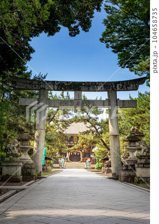 北野天満宮の初夏、鳥居の先の楼門に夏越の祓の茅の輪を見る 104658735