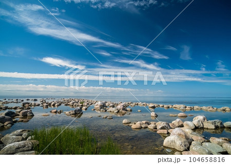 The rocky shore of the Baltic Sea. Beautiful sunny summer day, calm sea. Baltic Sea Estonia Kihnu Island. The rocky shore of the Baltic Sea. Beautiful sunny summer day, calm sea. Baltic Sea Estonia Kihnu Island. 104658816