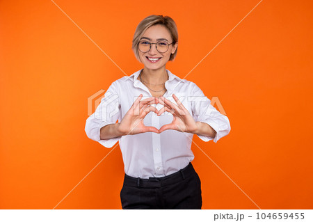 Romantic woman wearing white official style shirt showing heart shape with hands Romantic woman wearing white official style shirt showing heart shape with hands 104659455