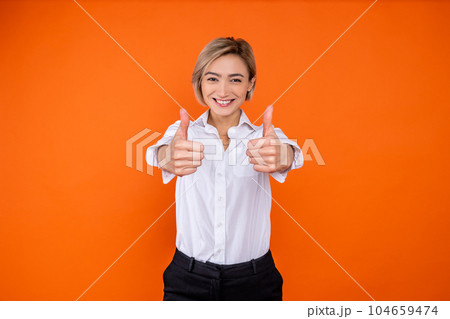 Positive woman wearing white official style shirt showing like gesture and smiling to camera 104659474