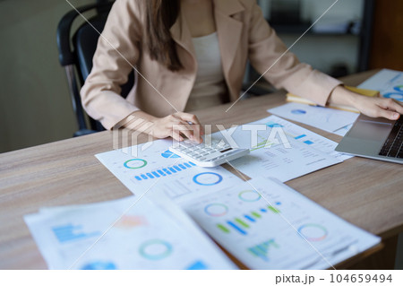 businesswoman or accountant working on calculator and laptop computer to calculate business data during using accountancy document at office. 104659494
