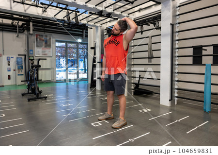 Handsome adult Caucasian man warm up and stretching neck before exercising in fitness gym Handsome adult Caucasian man warm up and stretching neck before exercising in fitness gym 104659831