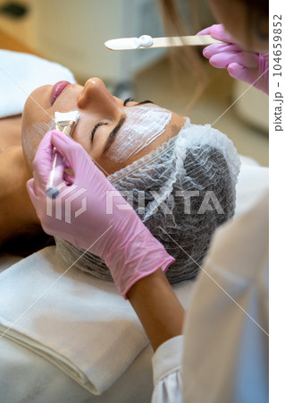 Professional beautician doing skin care procedures to woman client. 104659852