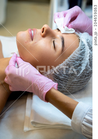 Beautician doctor doing cleansing face procedures to woman in cosmetology clinic. 104659863