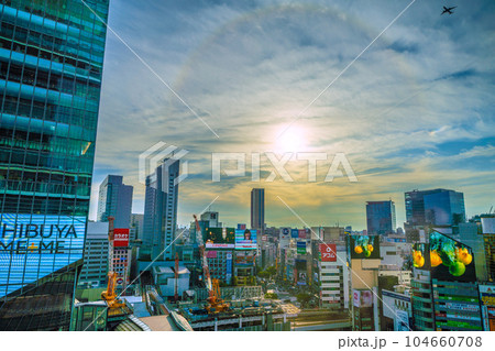 日本の東京都市景観 渋谷駅。沈む太陽の周りに現れた虹色の光の輪「ハロ」と航空機（珍景）＝7月2日 104660708