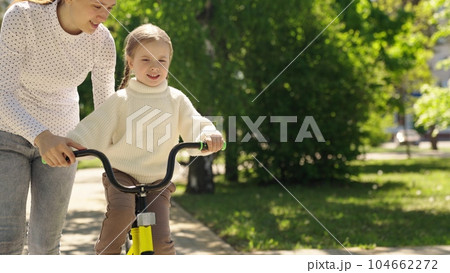 child learn ride bike. mother daughter girl park. happiness smile little child mom. dream family., mother teaches little smiling child ride bike, motherhood childhood, cardio, go faster, concept 104662272