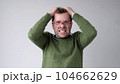 The young man with a panic attack is desperately tearing his hair on his head 104662629