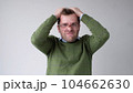 The young man with a panic attack is desperately tearing his hair on his head 104662630