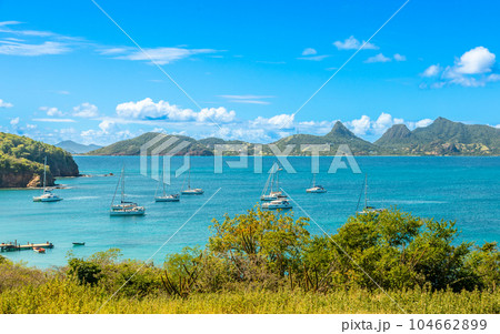 Lagoon with turquoise waters, yachts and boats at Mayreau island pier with Union island in the background, Saint Vincent and the Grenadines, West Indies, Caribbean Lagoon with turquoise waters, yachts and boats at Mayreau island pier with Union island in the background, Saint Vincent and the Grenadines, West Indies, Caribbean 104662899