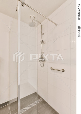 a bathroom with white tile walls and gray flooring the shower is clean and ready to be used for use 104663273