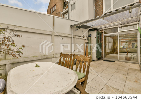 an outside area with a table, chairs and a tree in the middle of the patio looking out to the back yard 104663544
