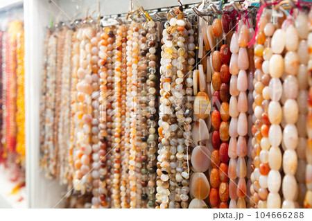 Beads from various semi-precious stones at the stand of jewelry store 104666288