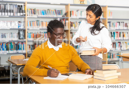Portrait of librarian handing book to man 104666307