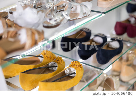 There are womens mustard,burgundy and dark blue ballet flats on glass window of store 104666486
