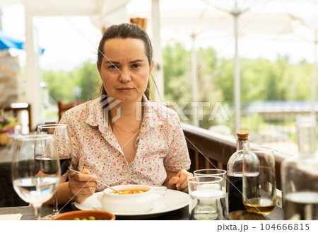 Positive woman eating tomato soup Gazpacho with bread 104666815