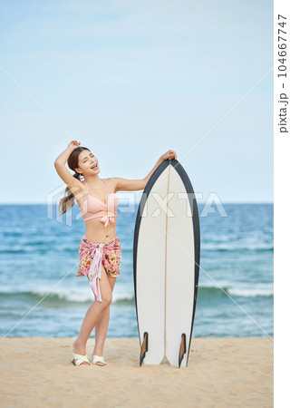 woman holding surfboard at beach 104667747
