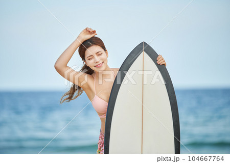 woman holding surfboard at beach 104667764
