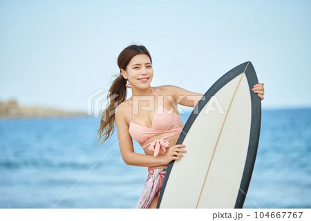 woman holding surfboard at beach 104667767
