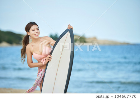 woman holding surfboard at beach 104667770