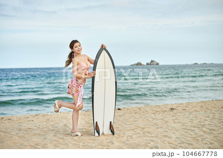 woman holding surfboard at beach 104667778