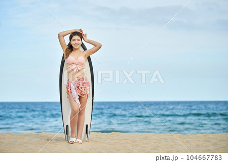 woman holding surfboard at beach 104667783