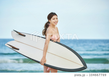 woman holding surfboard at beach 104667789