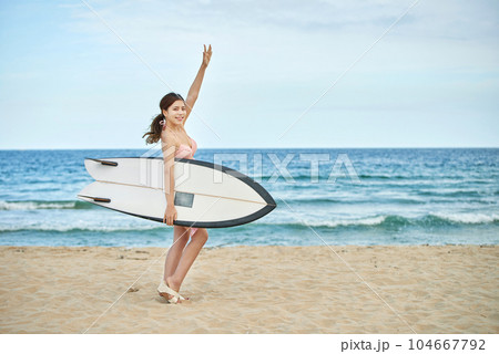 woman holding surfboard at beach 104667792