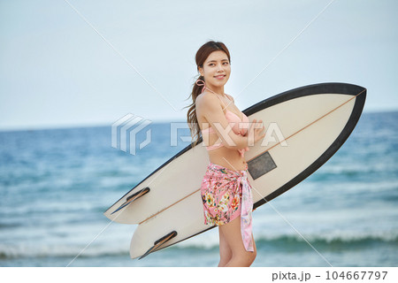 woman holding surfboard at beach 104667797