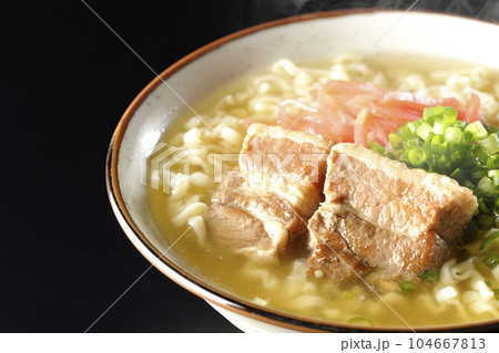 豚のバラ肉とたっぷりの小ねぎと紅生姜入りの熱々沖縄そばを黒背景で撮影 104667813