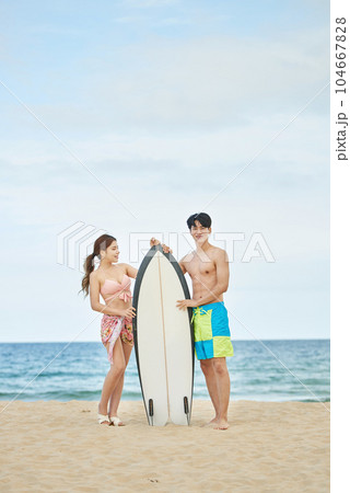 young male and female model holding a serving board on a summer beach 104667828