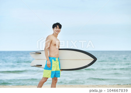 man holding surfboard at beach 104667839