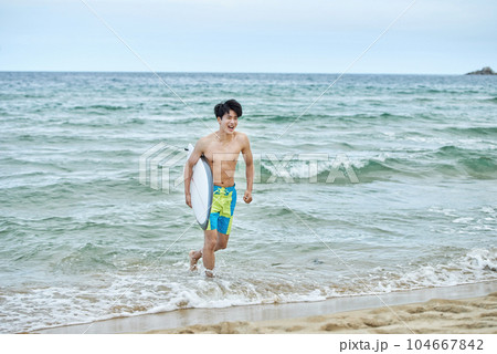 man holding surfboard at beach 104667842